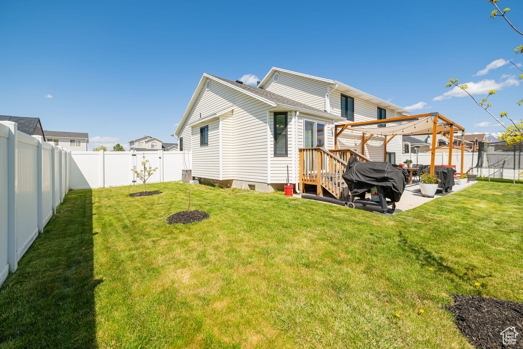 Rear view of property with a trampoline, a lawn, and a fenced backyard