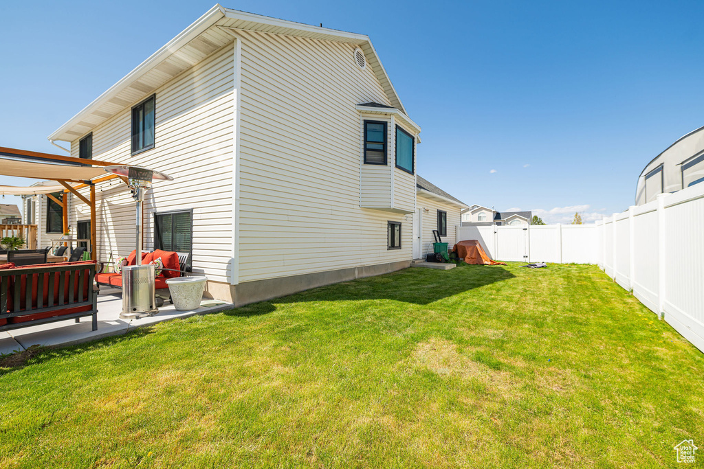 Back of property with a fenced backyard, outdoor lounge area, a patio area, and a lawn