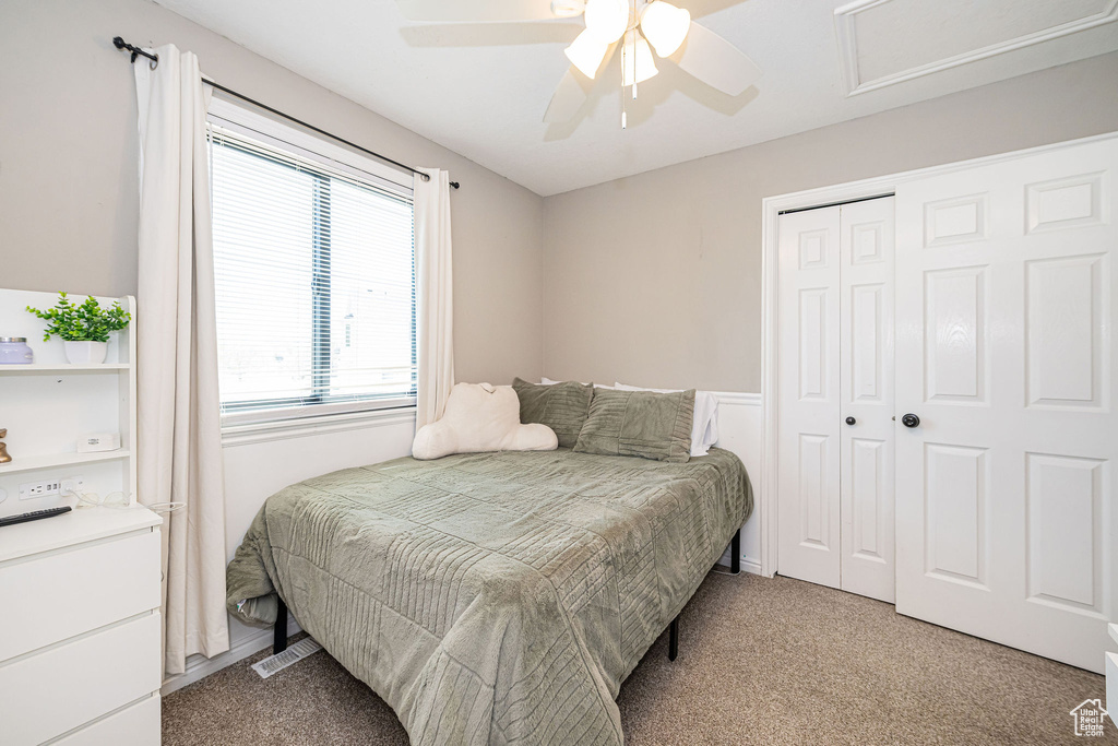 Bedroom with attic access, light carpet, visible vents, a ceiling fan, and a closet