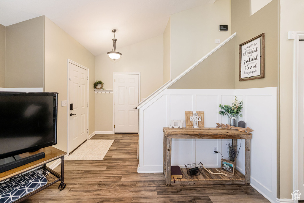 Foyer entrance featuring vaulted ceiling, wood finished floors, and a decorative wall