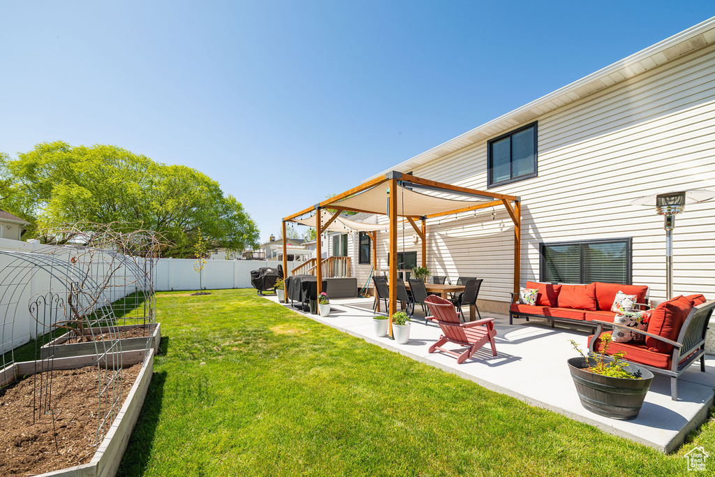 Rear view of house featuring a patio area, outdoor lounge area, a vegetable garden, a fenced backyard, and a yard