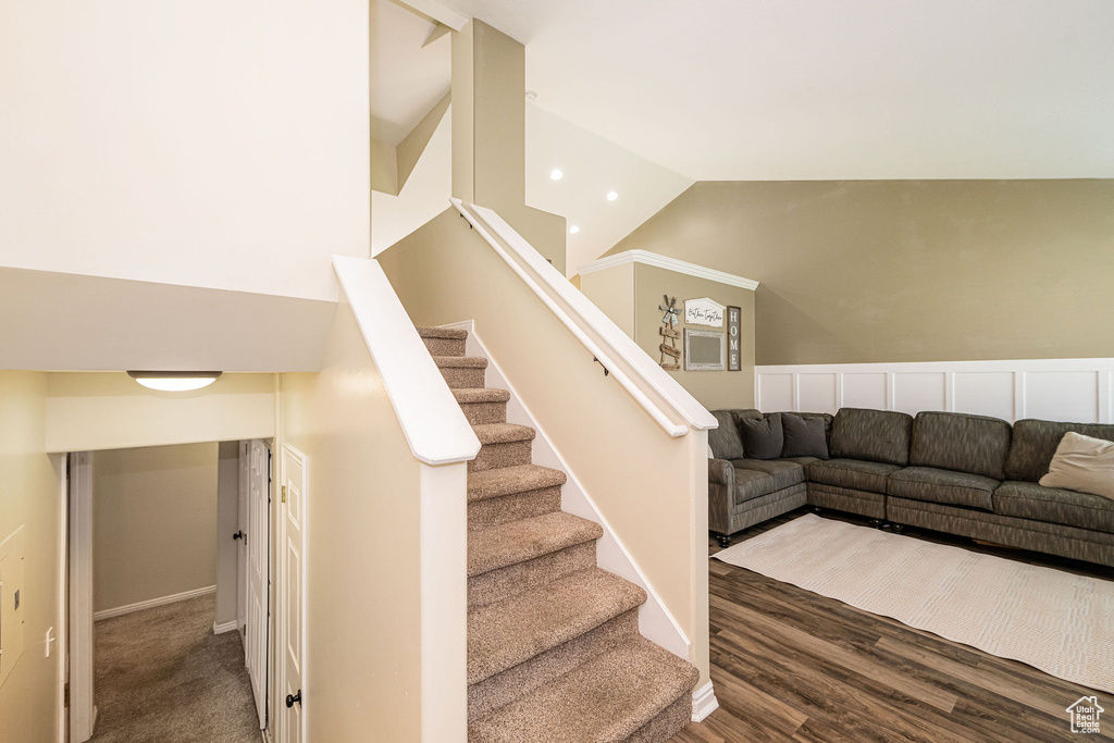 Staircase with high vaulted ceiling, baseboards, wood finished floors, and recessed lighting