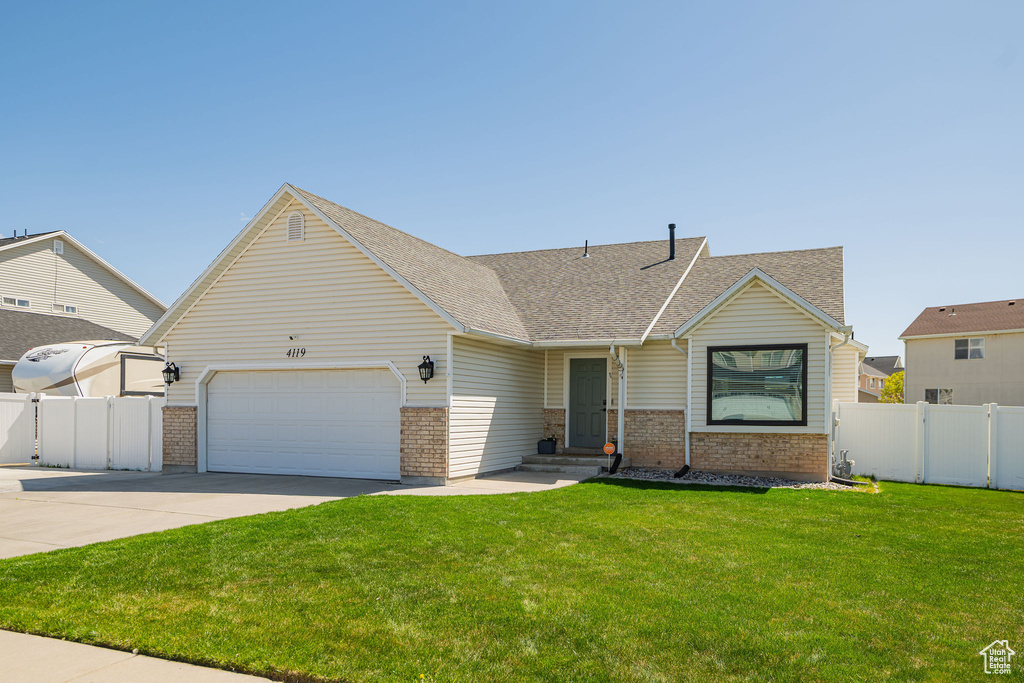 View of front of property featuring concrete driveway, a front lawn, fence, a garage, and brick siding