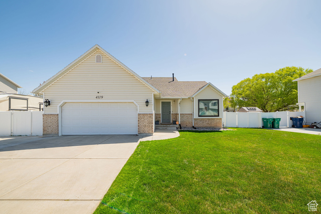 Single story home featuring a garage, driveway, a front yard, and fence