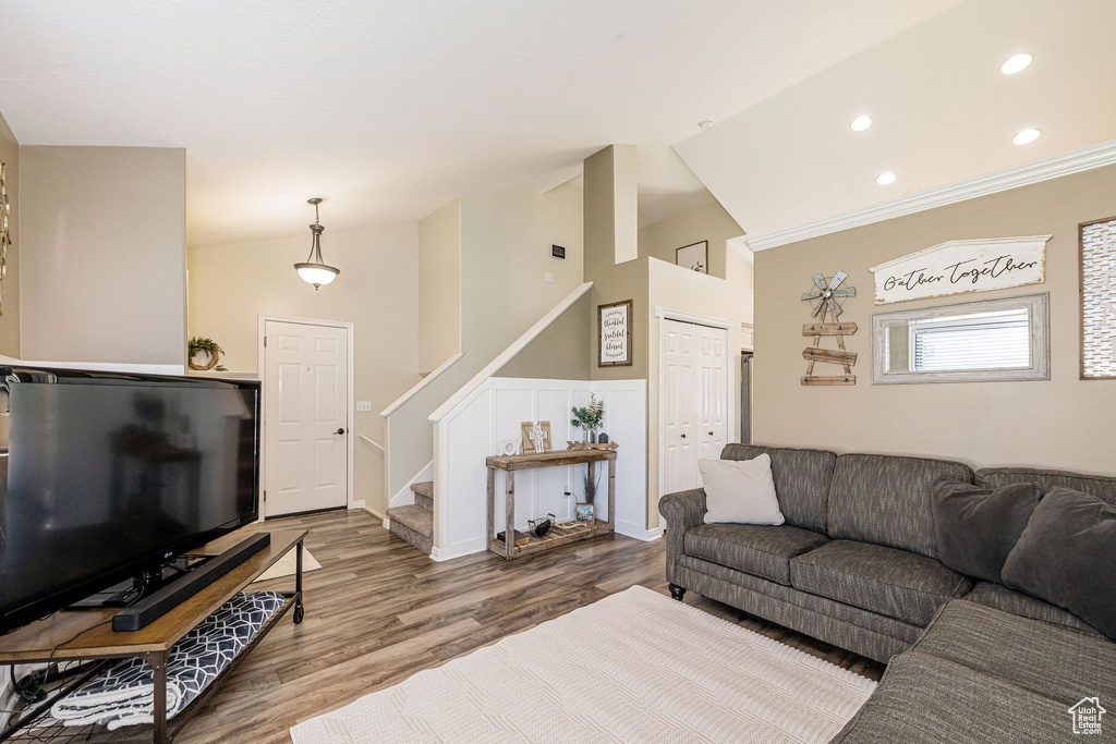 Living room with recessed lighting, vaulted ceiling, wood finished floors, and stairs