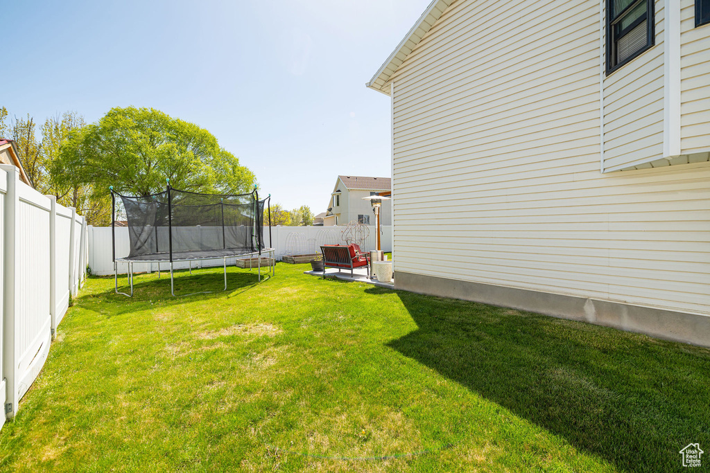 View of yard featuring a fenced backyard and a trampoline