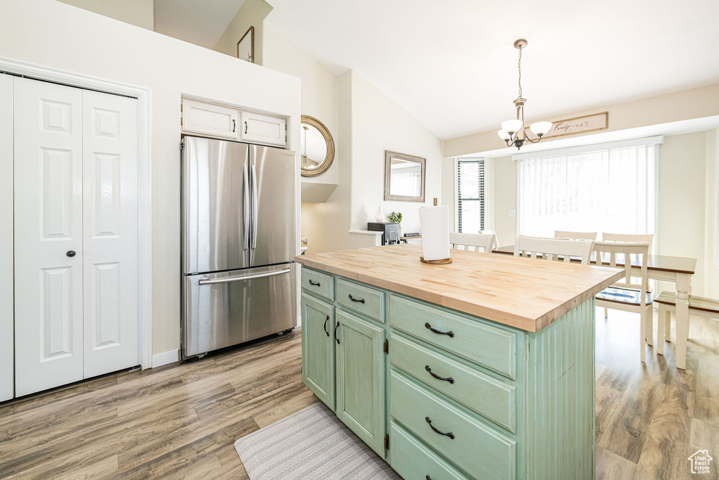 Kitchen with green cabinetry, light wood-type flooring, vaulted ceiling, freestanding refrigerator, and butcher block countertops