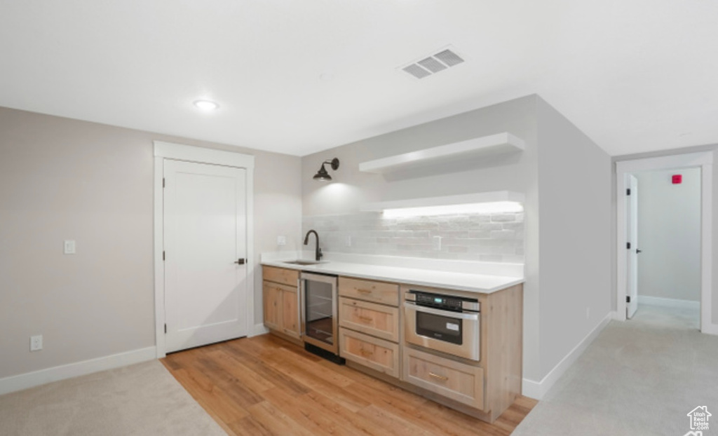Kitchen featuring oven, a sink, visible vents, open shelves, and beverage cooler