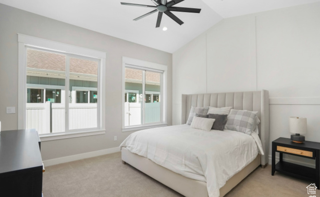 Bedroom with lofted ceiling, a ceiling fan, baseboards, and light colored carpet