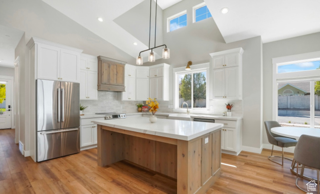 Kitchen with light countertops, a sink, stainless steel refrigerator, and white cabinetry
