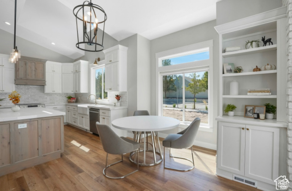 Kitchen with stainless steel dishwasher, visible vents, decorative backsplash, wood finished floors, and hanging light fixtures