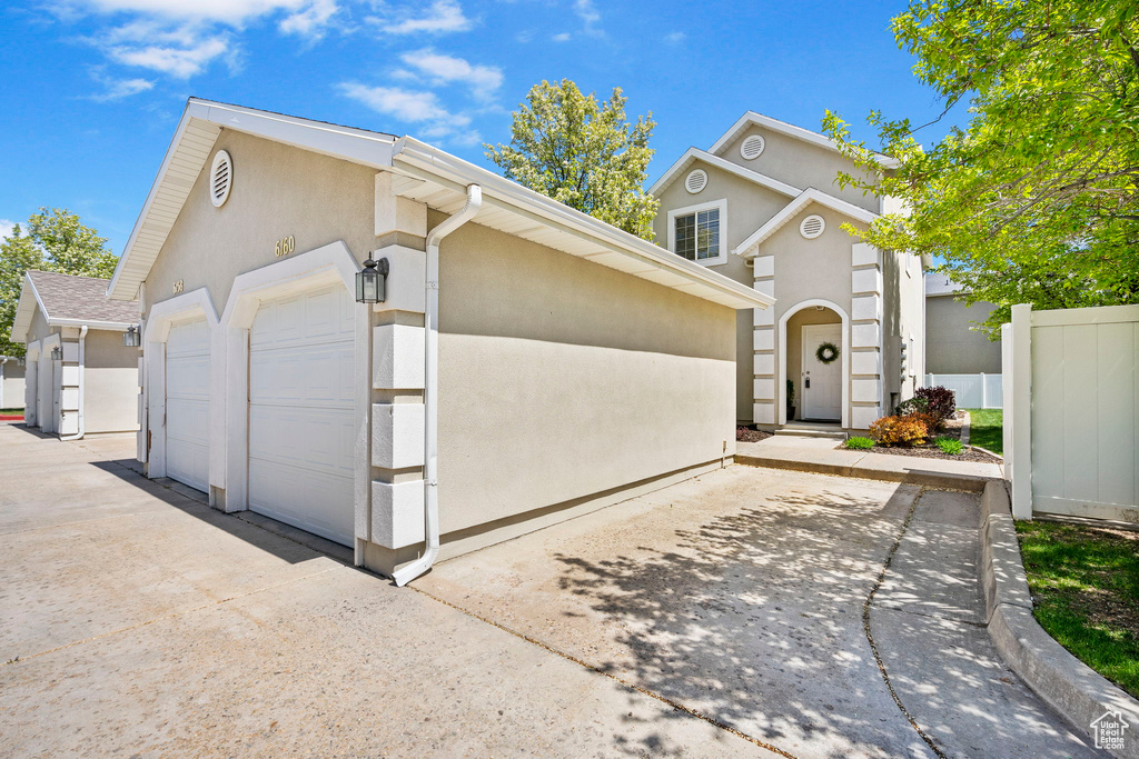 View of front facade with fence, an outdoor structure, and stucco siding