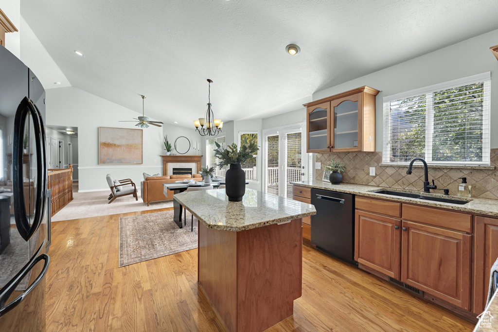 Kitchen with a center island, a sink, black appliances, glass insert cabinets, and a fireplace