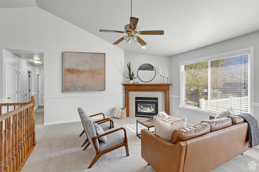 Carpeted living area with a fireplace with flush hearth, vaulted ceiling, baseboards, and ceiling fan