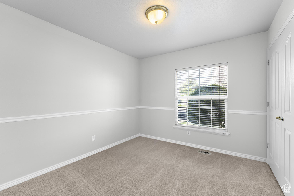 Carpeted empty room with baseboards and visible vents