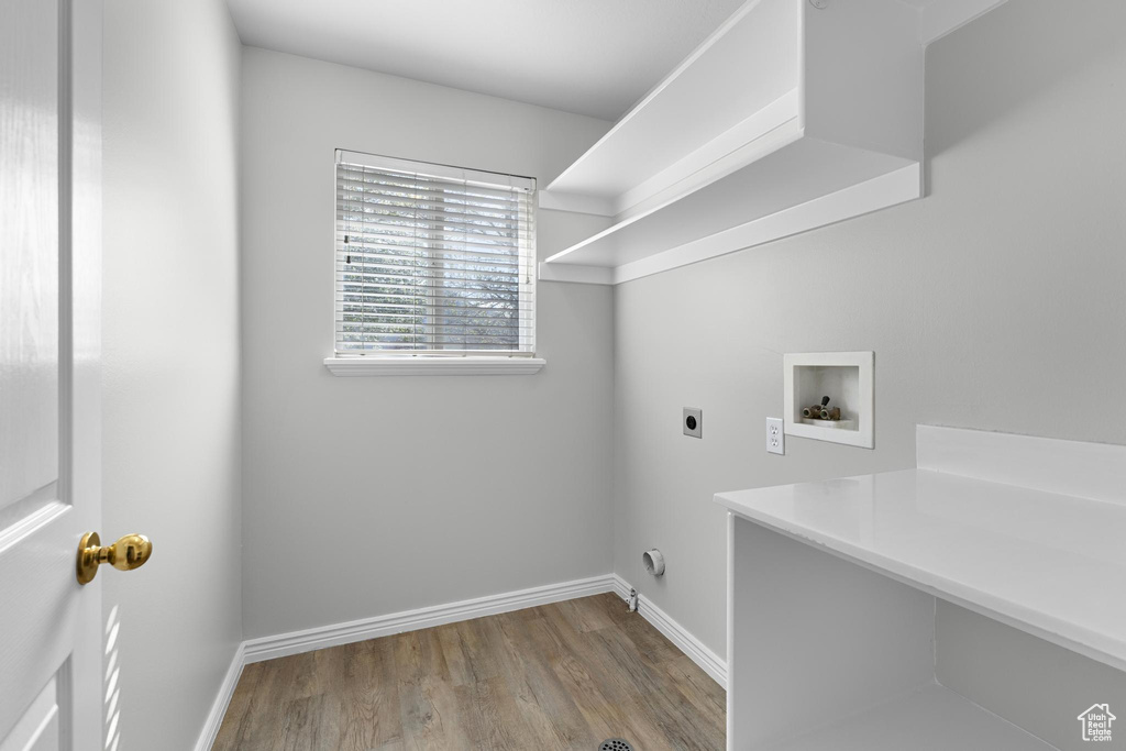 Laundry area with baseboards, hookup for a washing machine, wood finished floors, electric dryer hookup, and laundry area