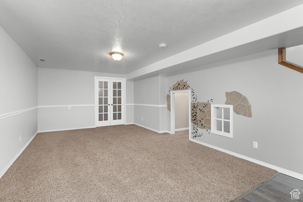 Carpeted empty room featuring visible vents, french doors, baseboards, and a textured ceiling