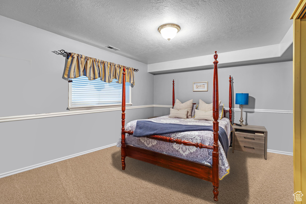 Bedroom with carpet floors, a textured ceiling, baseboards, and visible vents