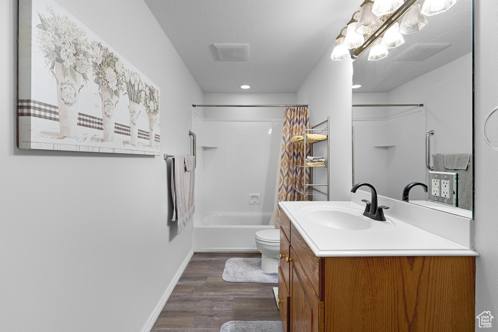 Full bathroom with toilet, recessed lighting, shower / tub combo with curtain, wood finished floors, and vanity
