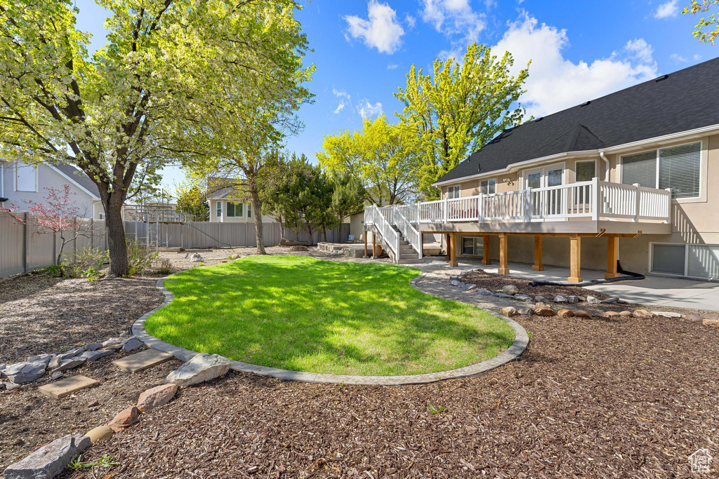 View of yard featuring a fenced backyard, a wooden deck, stairway, and a patio