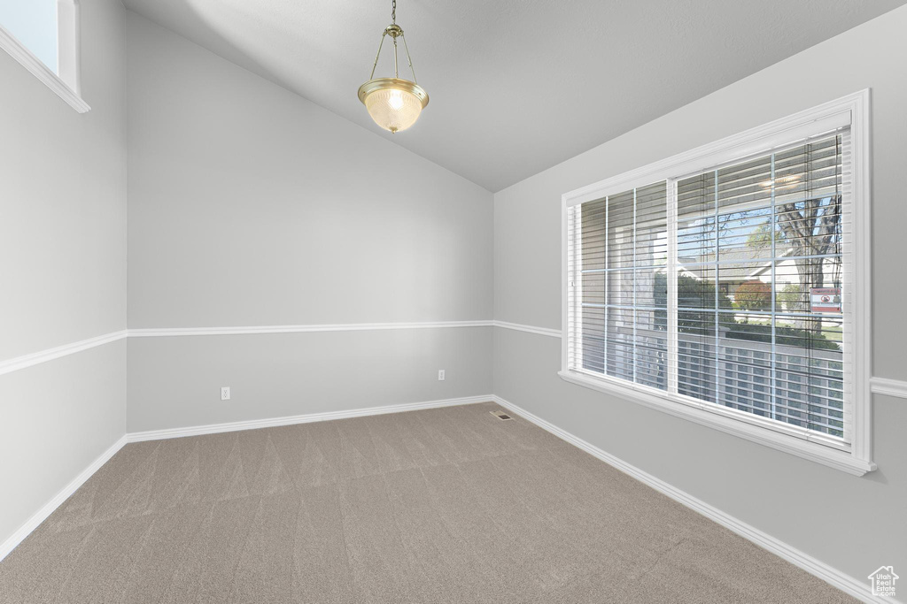 Carpeted spare room with lofted ceiling and baseboards