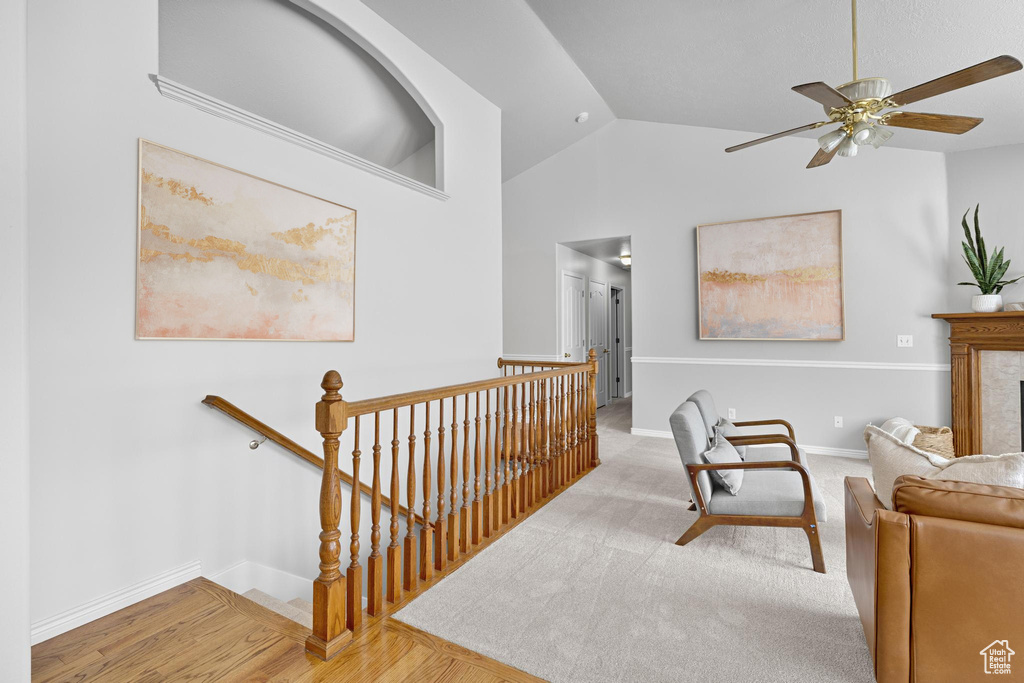 Living area featuring vaulted ceiling, baseboards, an upstairs landing, a ceiling fan, and a fireplace