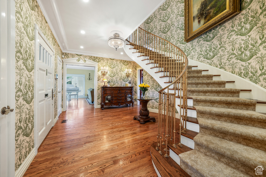 Entryway featuring wallpapered walls, ornamental molding, stairs, light wood-style floors, and recessed lighting