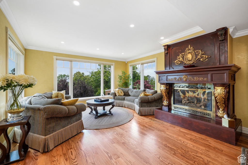 Living area with a premium fireplace, wood finished floors, crown molding, and recessed lighting