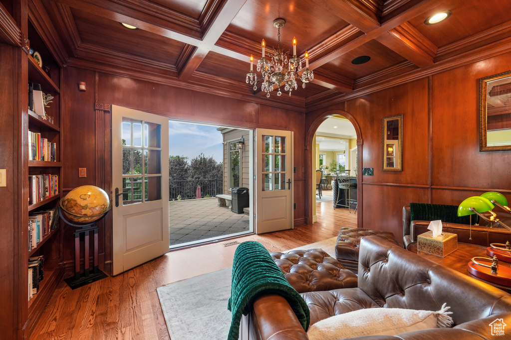Living area with crown molding, wooden walls, wood finished floors, a wooden ceiling with exposed beams, and coffered ceiling