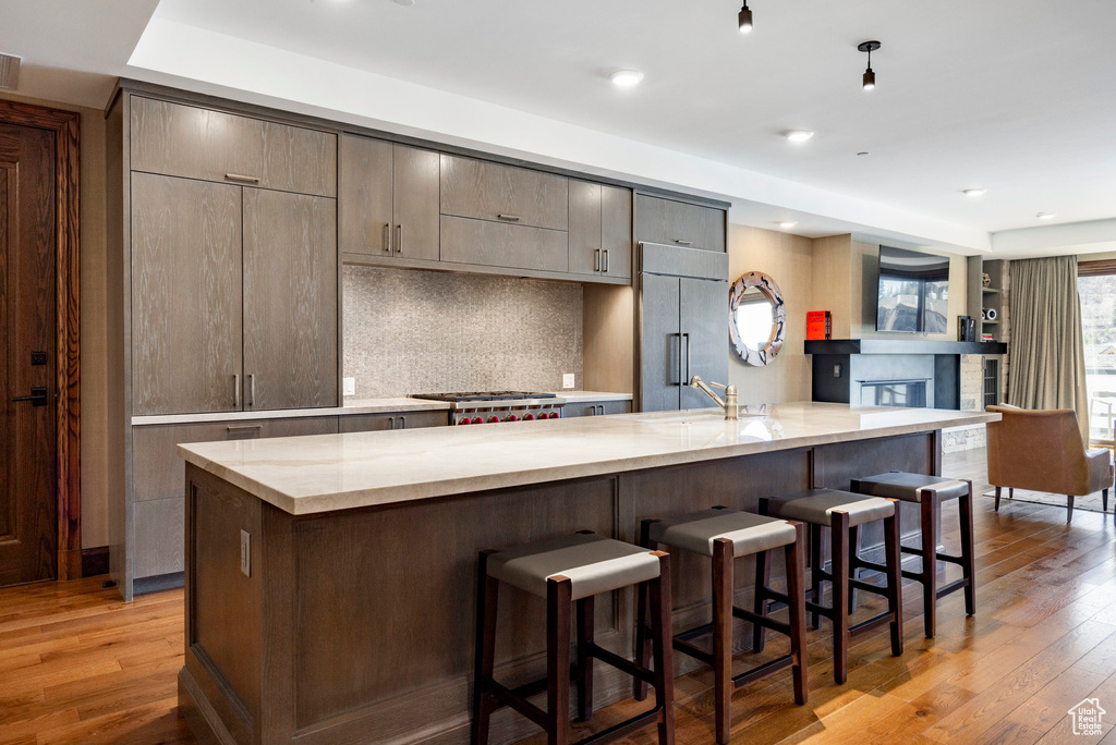 Kitchen with light wood-style flooring, backsplash, a breakfast bar area, and built in refrigerator