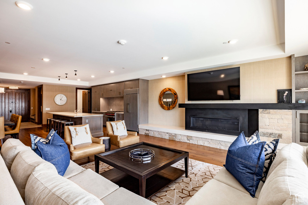 Living room with a fireplace, light wood finished floors, and recessed lighting