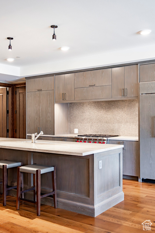 Kitchen with backsplash, light countertops, refrigerator, and a breakfast bar area