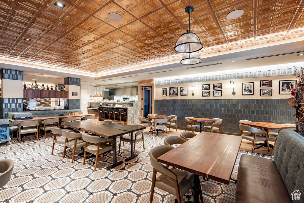 Dining space with a raised ceiling, an ornate ceiling, and a wainscoted wall