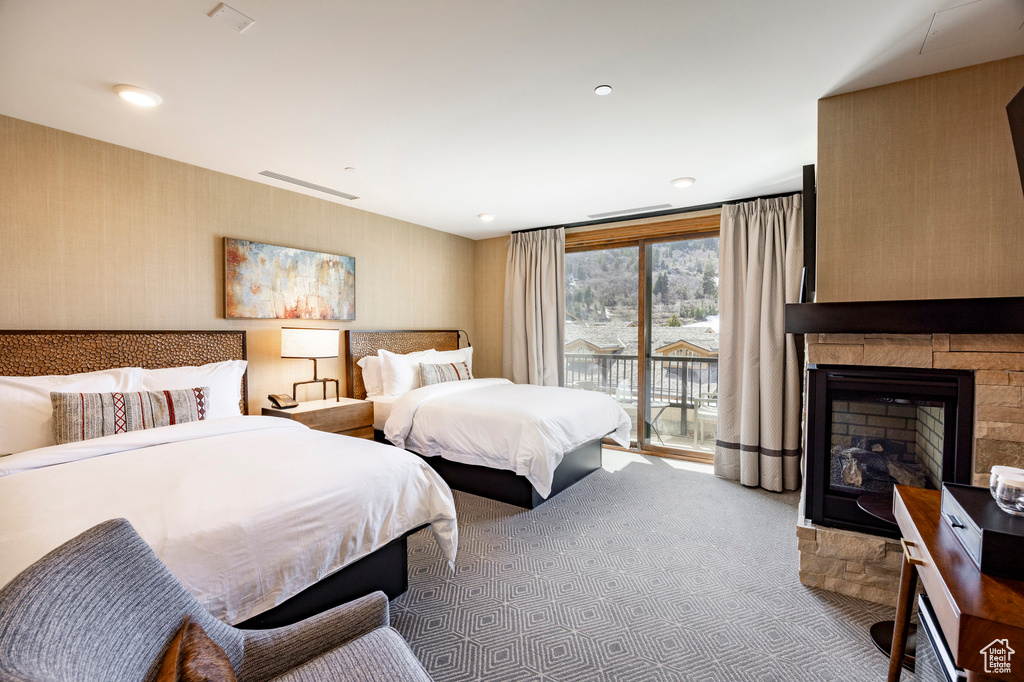 Carpeted bedroom featuring wallpapered walls, a fireplace, and access to outside