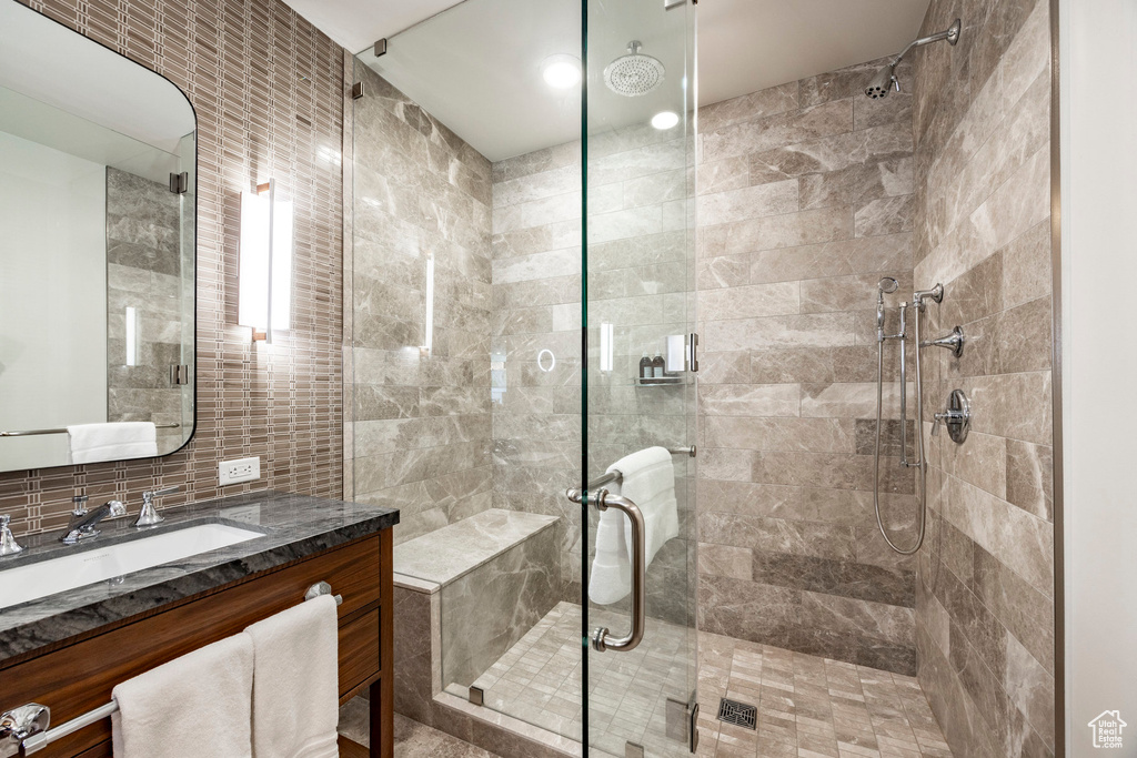 Full bathroom with backsplash, tile walls, vanity, and a stall shower