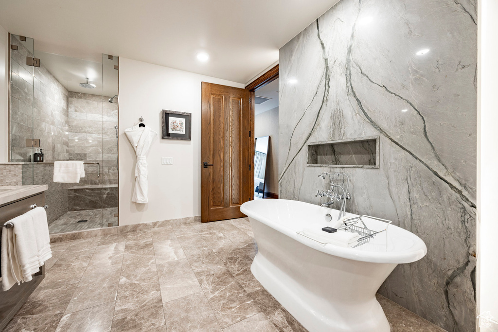 Bathroom with a tile shower, a freestanding tub, and vanity