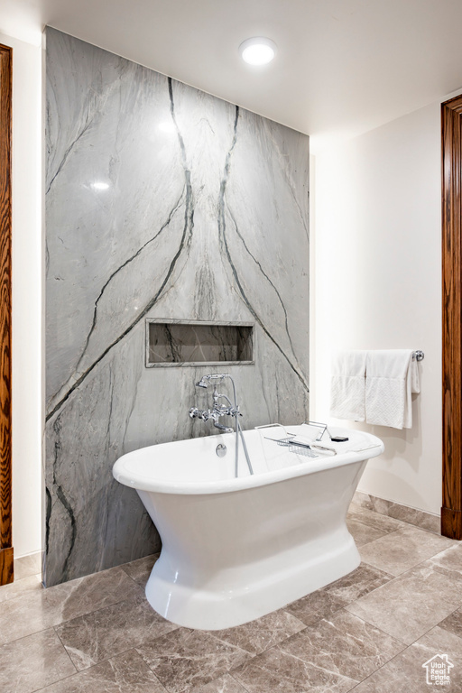 Full bathroom with tile walls, baseboards, a freestanding tub, and marble finish floor