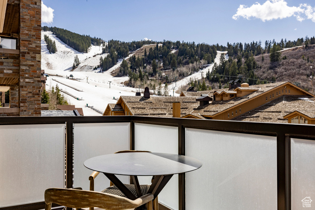 Snow covered back of property with outdoor dining space and a mountain view