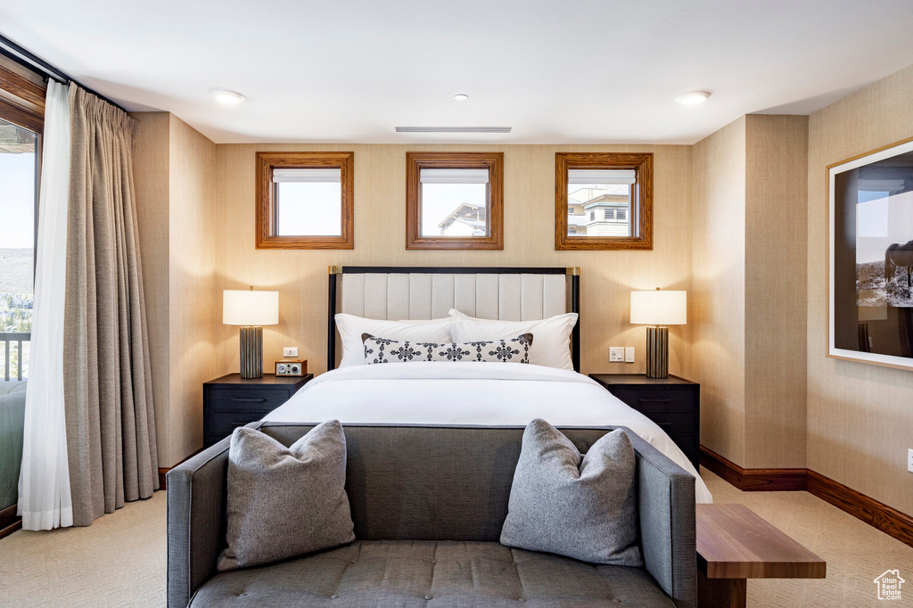 Bedroom with wallpapered walls, baseboards, and carpet flooring
