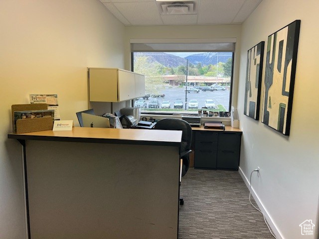 Office area featuring dark colored carpet, visible vents, and baseboards