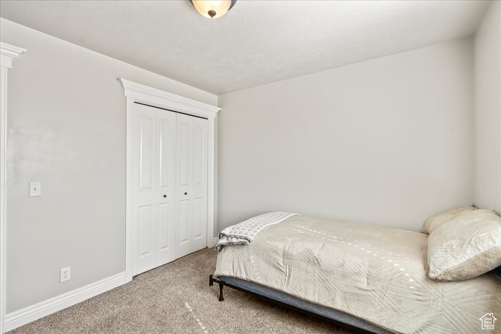 Carpeted bedroom featuring baseboards and a closet