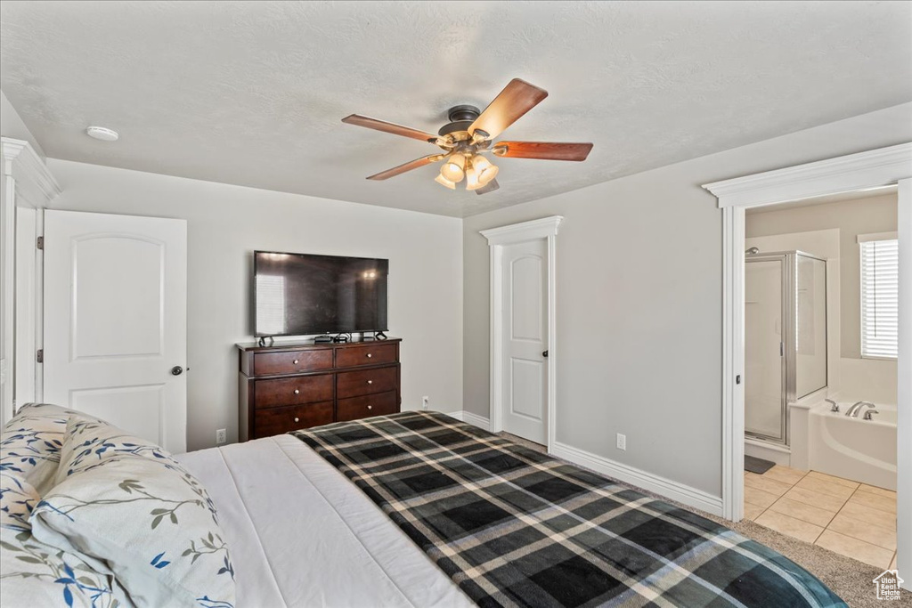 Tiled bedroom with connected bathroom, ceiling fan, and baseboards