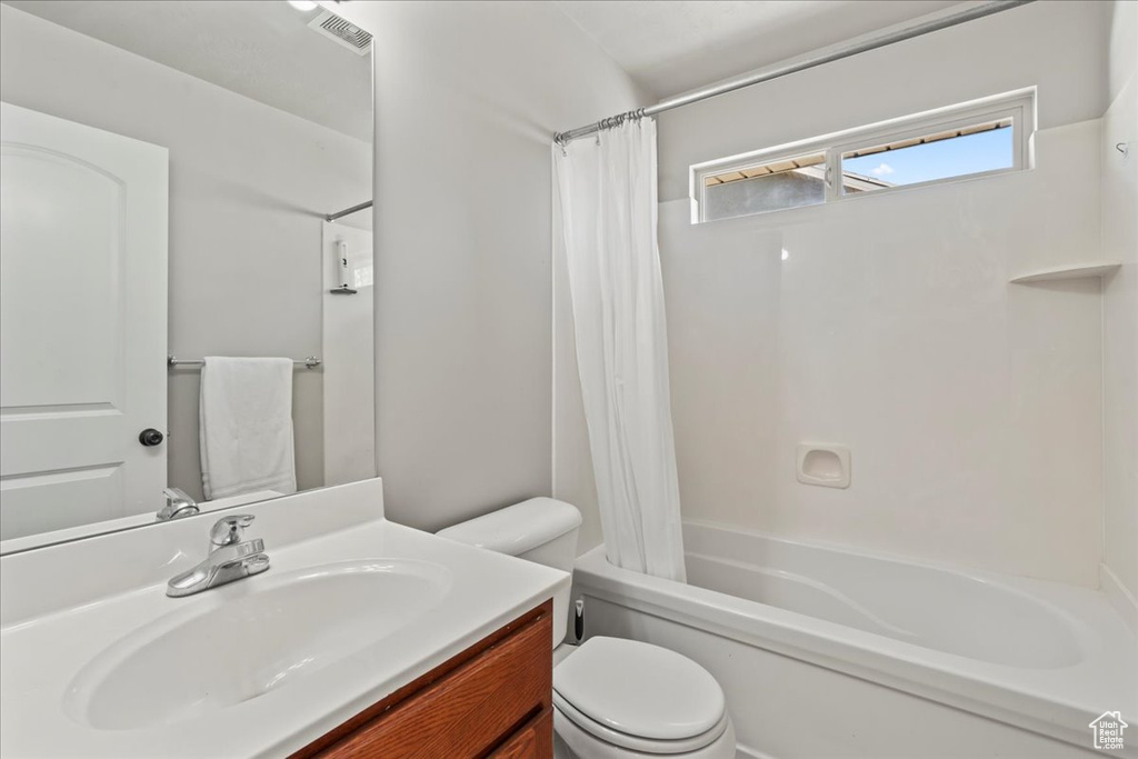 Full bathroom with shower / bath combination with curtain, visible vents, vanity, and toilet