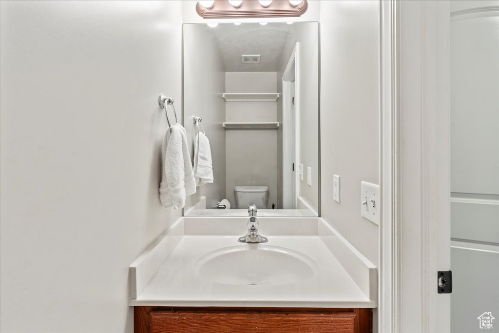 Bathroom featuring visible vents, vanity, and toilet