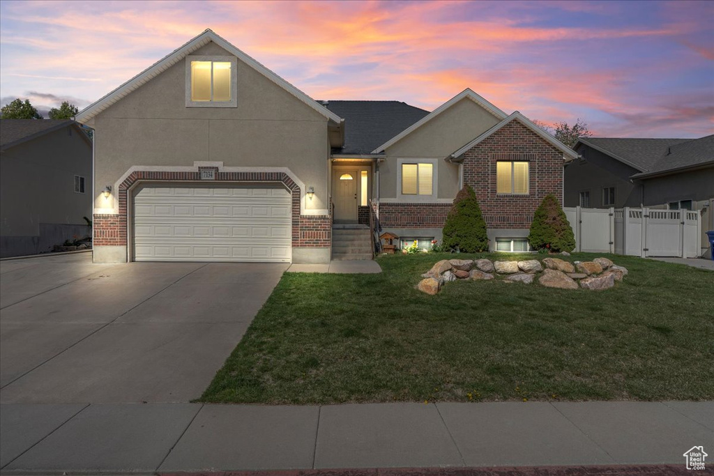 View of front of property with a gate, concrete driveway, a front yard, stucco siding, and brick siding
