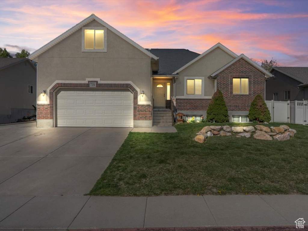 View of front of property with a gate, concrete driveway, a front yard, stucco siding, and brick siding