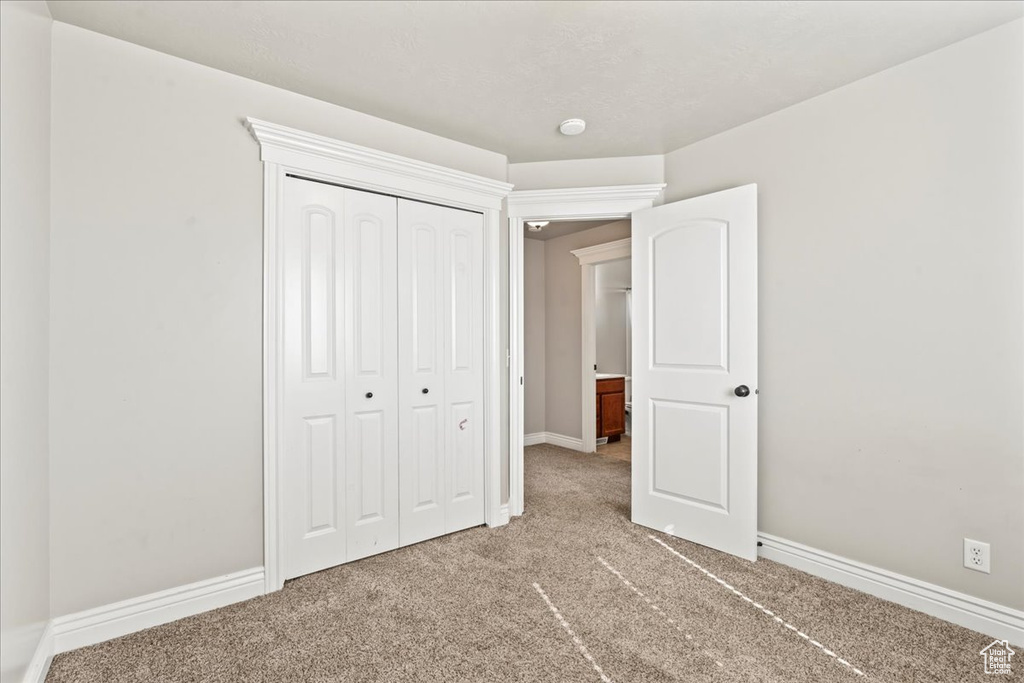 Unfurnished bedroom with light colored carpet, baseboards, and a closet