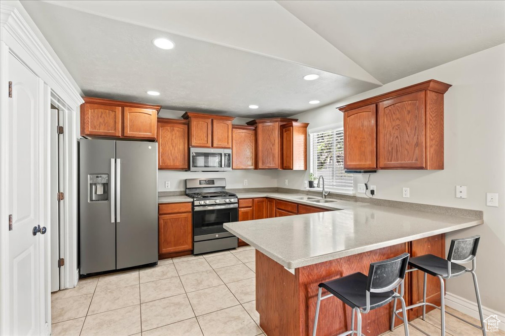 Kitchen with recessed lighting, stainless steel appliances, a sink, a peninsula, and brown cabinetry