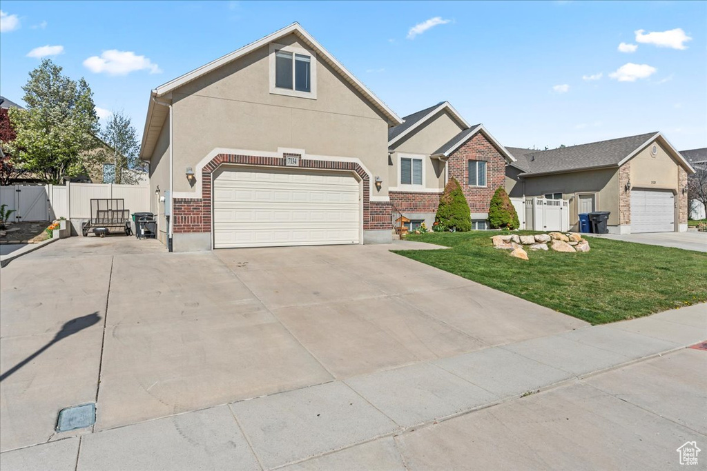 View of front facade with concrete driveway, a front yard, stucco siding, and fence
