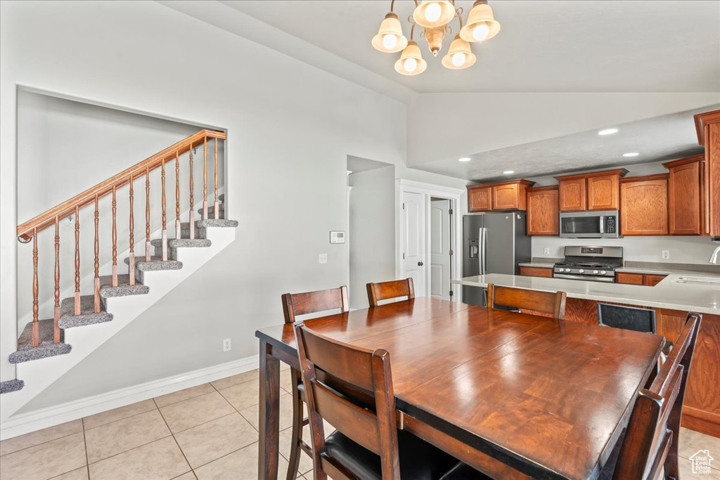 Dining room featuring vaulted ceiling, stairs, light tile patterned floors, an inviting chandelier, and baseboards